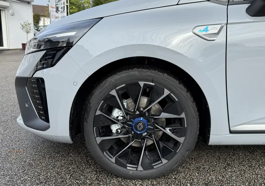 Gros plan sur la roue avant gauche noire et grise d'une Renault Clio V gris Rafale avec logo Esprit Alpine bleu.