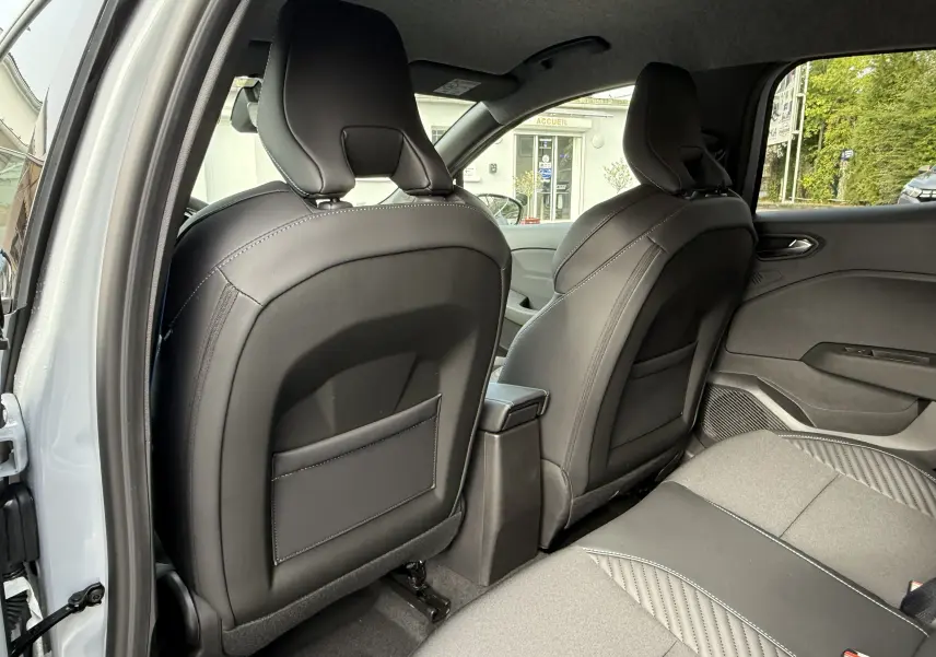 Vue arrière intérieure montrant les sièges avant en cuir noir et la banquette arrière grise de la Renault Clio V Gris Rafale 2025.