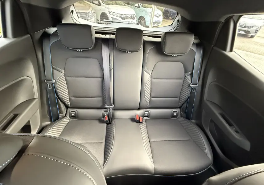 Vue intérieure arrière des sièges noirs avec surpiqûres bleues de la Renault Clio V hybride gris Rafale 2025.