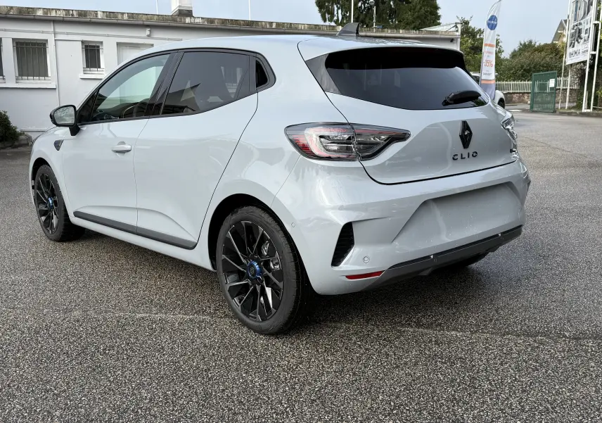 Vue 3/4 arrière droite d'une Renault Clio V gris Rafale 2025 avec jantes noires et vitres teintées.