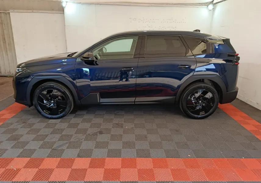 Vue latérale droite d'un Citroën C5 hybride bleu foncé avec jantes noires et toit noir dans un garage.