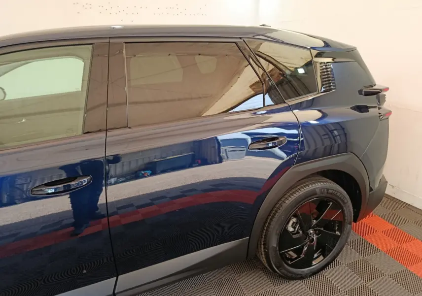 Vue latérale droite sur l'arrière d'une Citroën C5 hybride bleue avec jante noire et vitres teintées.