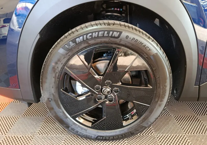 Gros plan sur la roue avant droite d'une Citroën C5 hybride bleue avec jante noire brillante et pneu Michelin.