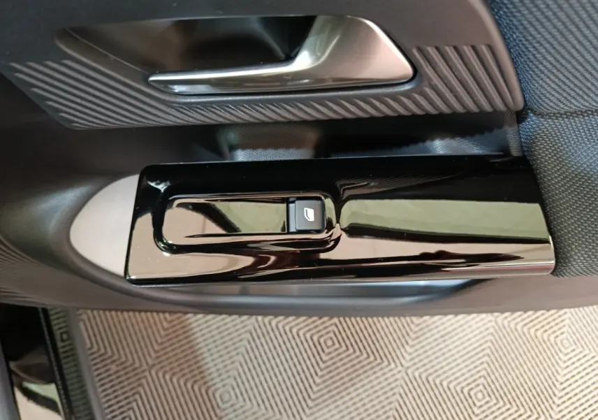 Gros plan sur la commande de lève-vitre noir brillant et la poignée intérieure côté conducteur d'une Citroën C5 Hybride 2026.