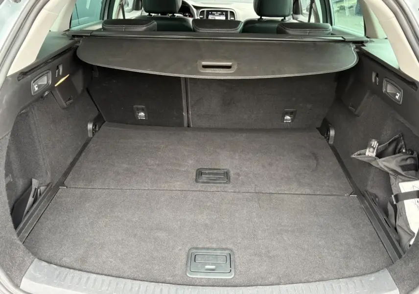 Coffre ouvert de la Renault Mégane Break gris Highland, montrant un espace de chargement spacieux et tapis noir.