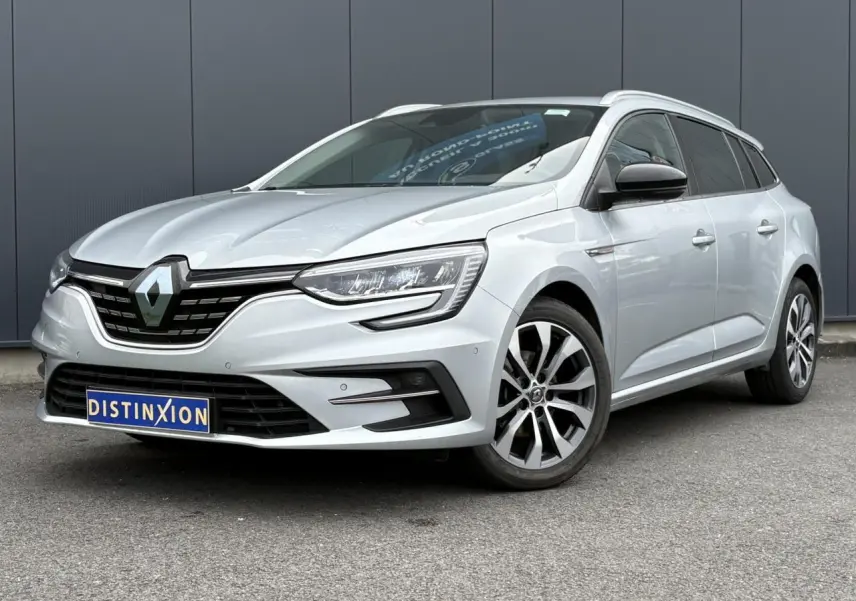 Renault Mégane Break gris clair en 3/4 avant droit, avec jantes alliage et calandre noire distinctive.