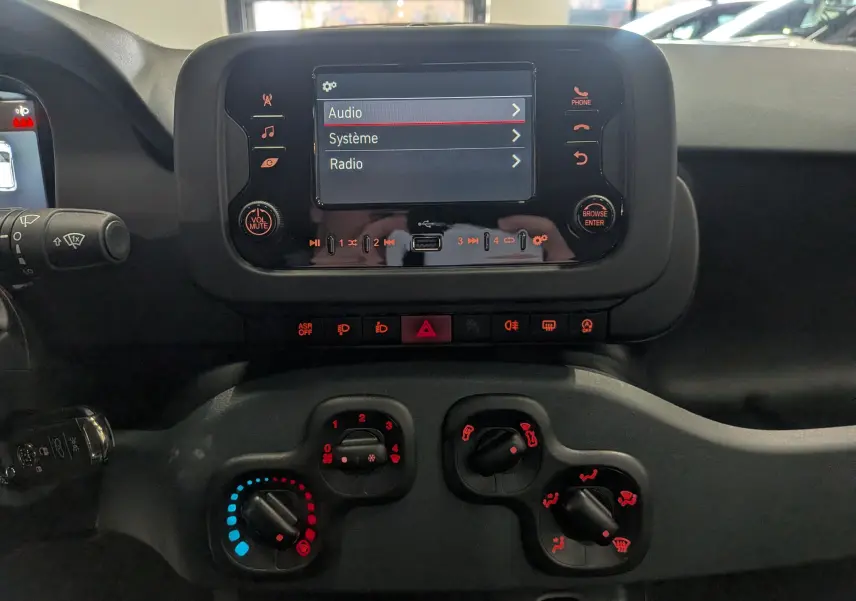 Vue rapprochée du tableau de bord de la Fiat Panda 1.0 Hybrid 2025, avec écran central et commandes climatisation visibles.