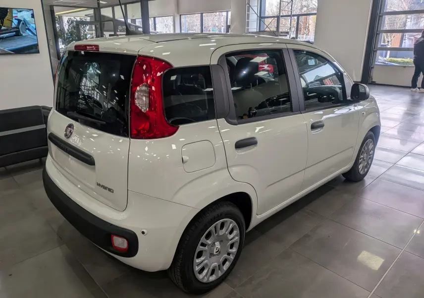 Vue 3/4 arrière droite de la FIAT Panda 1.0 Hybrid 2025 en blanc Gelato, avec feux arrière rouges et jantes argentées.