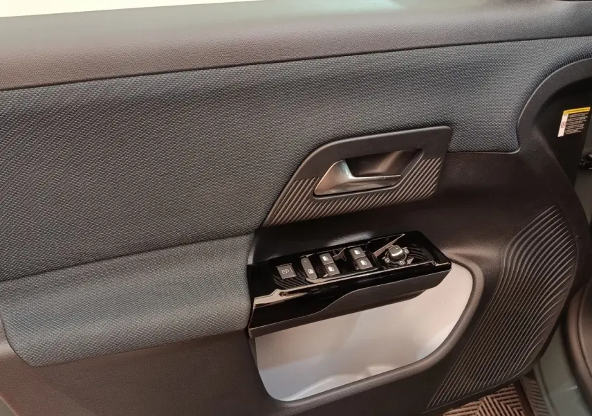 Gros plan sur la porte intérieure côté gauche de la Citroën C5 Hybride 2026, avec commandes de vitres et poignée noire.