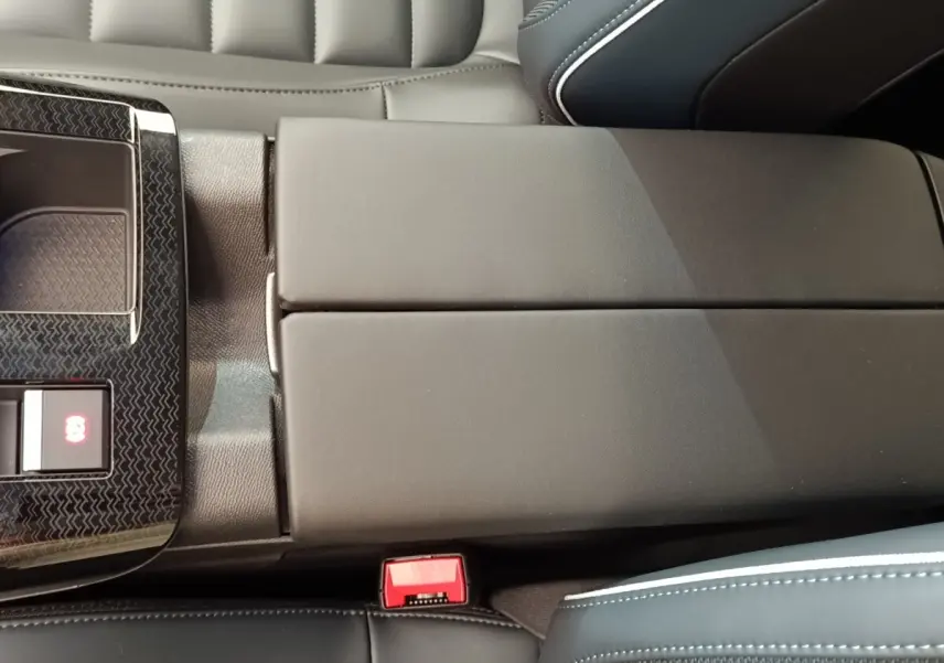 Vue rapprochée de l'accoudoir central noir et des sièges en cuir avec surpiqûres blanches dans l'habitacle d'une Citroën C5 Hybride.