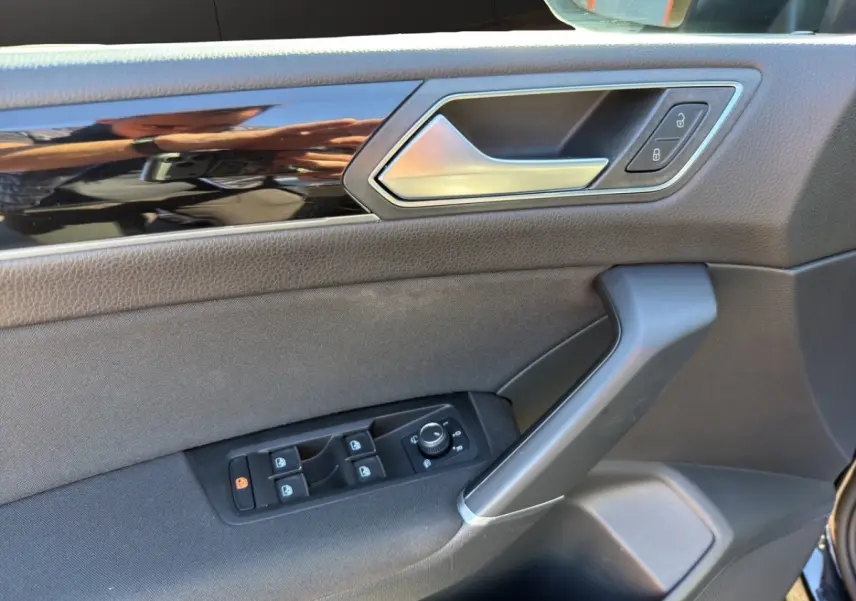 Vue rapprochée de la porte avant gauche noire du Volkswagen Touran 2016, avec commandes de vitres et poignée alu.