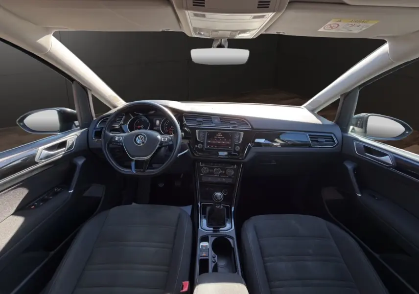 Vue intérieure avant du Volkswagen Touran 2016 noir, volant multifonctions cuir et alu, tableau de bord avec écran tactile central.
