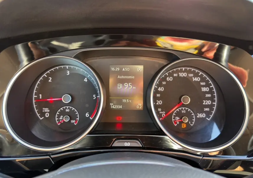 Tableau de bord du Volkswagen Touran 2016 avec compte-tours, vitesse, écran digital affichant autonomie et température.