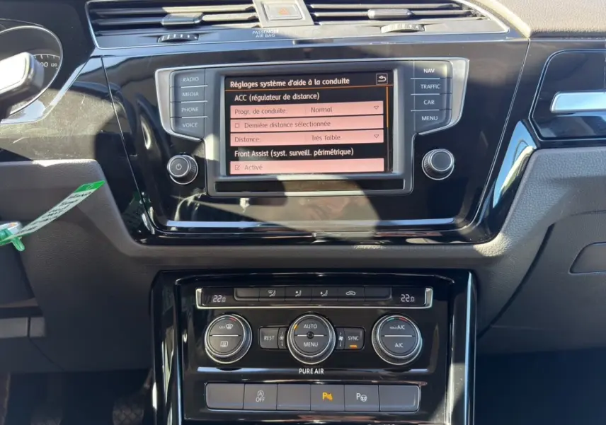 Vue rapprochée du tableau de bord noir du Volkswagen Touran 2016 avec écran tactile et commandes climatisation.