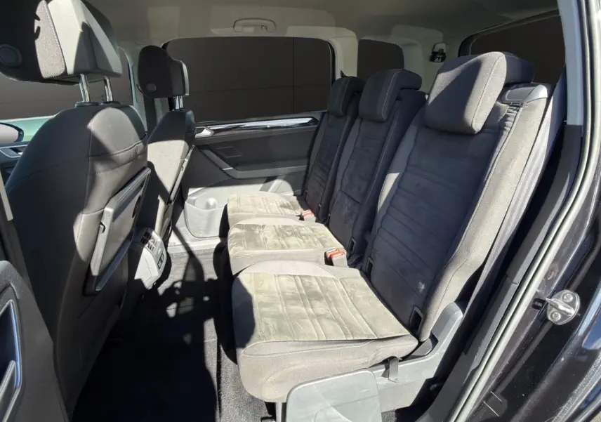 Vue intérieure côté droit des sièges arrière en tissu gris du Volkswagen Touran noir, version 7 places avec porte ouverte.