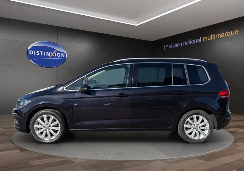 Volkswagen Touran noir vu de profil côté gauche, avec jantes alliage et toit chromé en showroom.