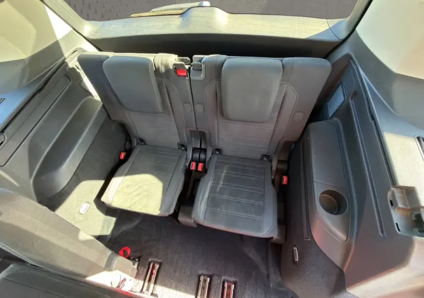 Vue plongeante sur la troisième rangée de sièges noirs du Volkswagen Touran 2016, avec accoudoir et espace de coffre visible.