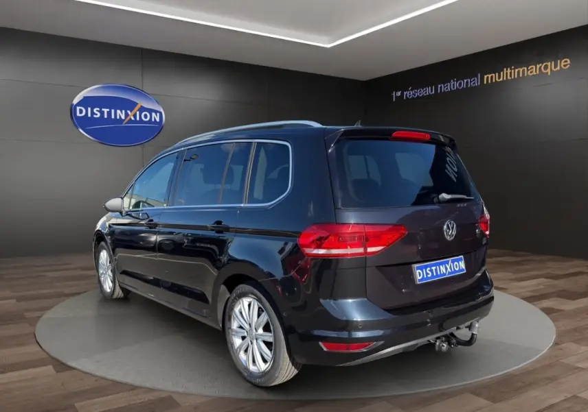 Volkswagen Touran noir vue 3/4 arrière droit, avec attelage et jantes alliage visibles en showroom.