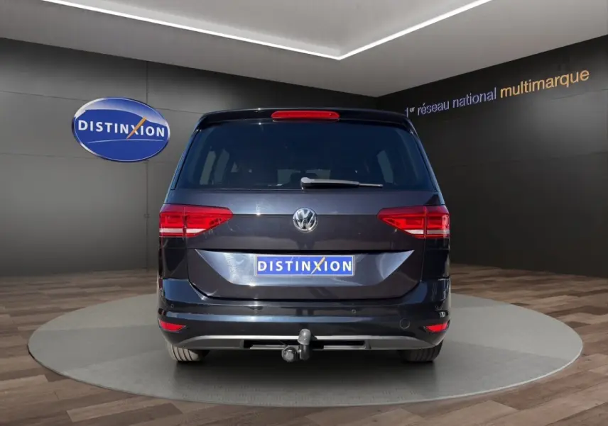 Vue arrière d'un Volkswagen Touran noir 2016 avec attelage visible sur fond de showroom Distinxion.