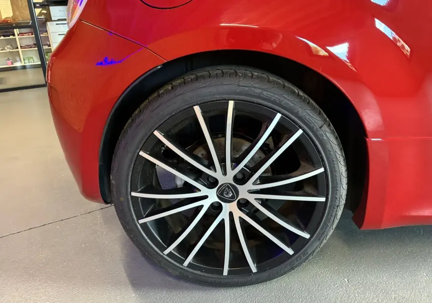 Gros plan sur la roue arrière droite rouge d'une ABARTH 500 595 Competizione avec jante noire et argentée à rayons fins.