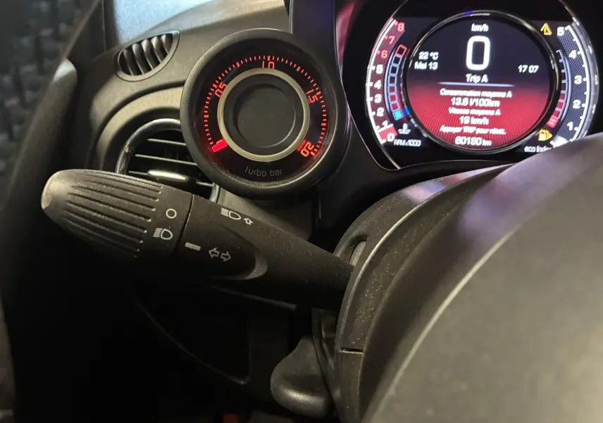 Gros plan sur le tableau de bord de l'Abarth 500 rouge, montrant le manomètre turbo et l'affichage numérique du compteur.