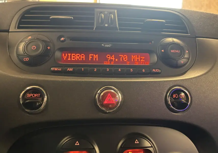 Tableau de bord de l'Abarth 500 rouge 2016, vue centrale sur autoradio et boutons sport et feux antibrouillard.