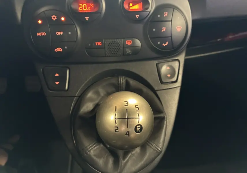 Gros plan sur le levier de vitesses manuel argenté et la console centrale noire d'une Abarth 500 rouge de 2016.