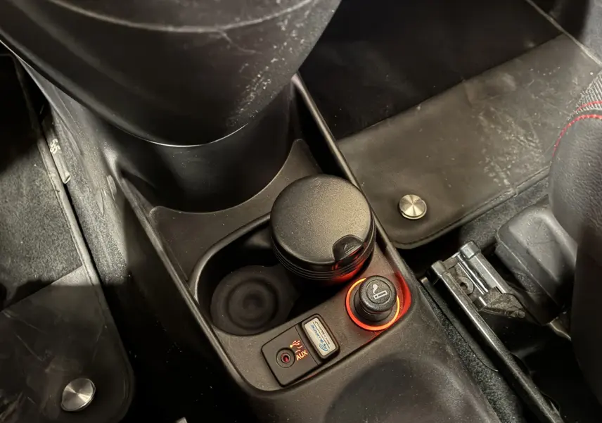 Gros plan sur la console centrale de l'Abarth 500 rouge 2016, montrant l'allume-cigare et prise auxiliaire éclairés en rouge.