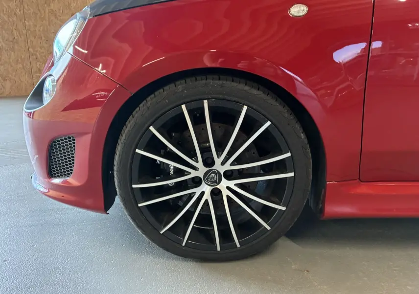 Gros plan sur la roue avant gauche de l'Abarth 500 rouge 2016 avec jante noire et rayures argentées distinctives.