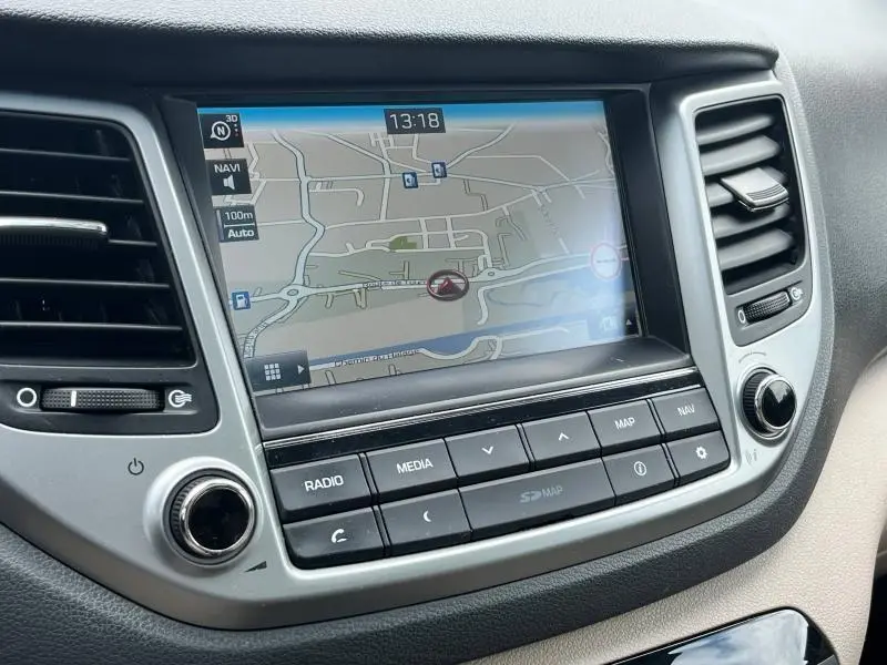 Vue rapprochée de l'écran tactile GPS du tableau de bord gris du Hyundai Tucson 2017 avec commandes audio intégrées.