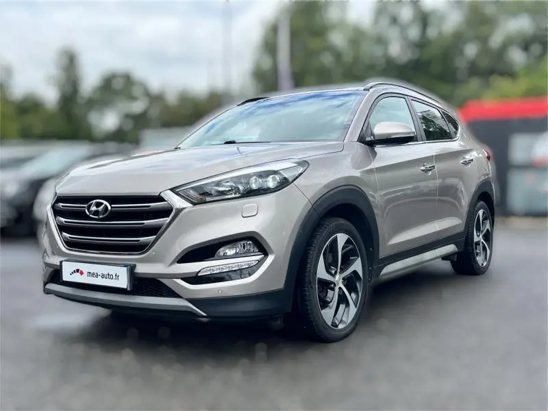 Vue 3/4 avant droite d'un Hyundai Tucson 2017 blanc sable avec jantes alliage et calandre chromée.
