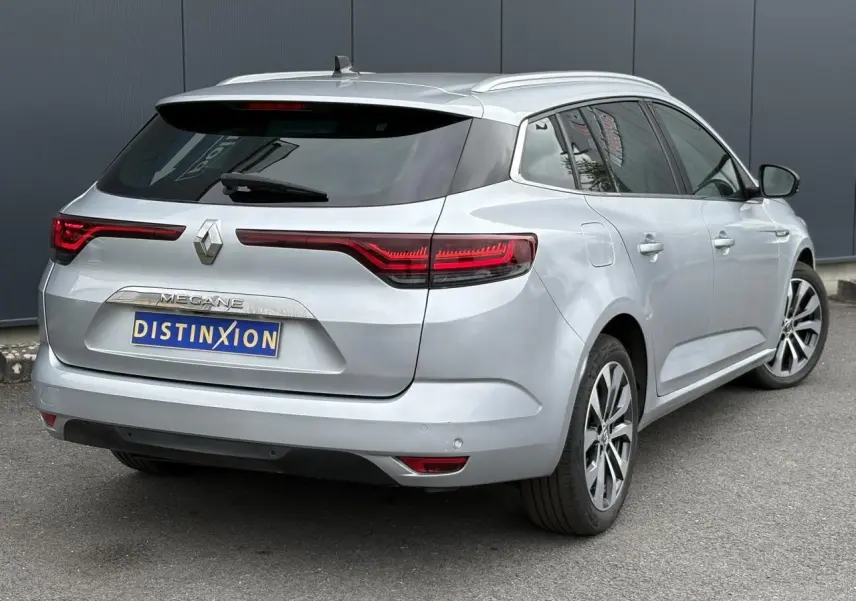 Vue 3/4 arrière droite d'une Renault Mégane Break 2024 gris Highland avec feux arrière LED et jantes alliage.