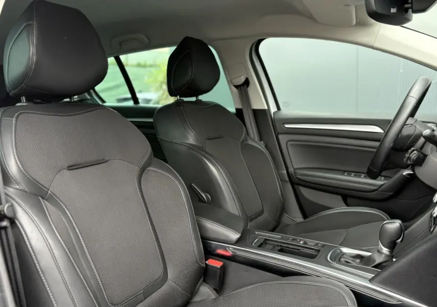 Vue intérieure côté conducteur et passager avant de la Renault Mégane Break 2024 avec sellerie mixte similicuir et tissu carbone.