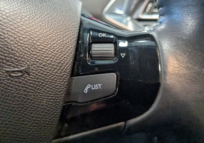 Gros plan sur les commandes noires du volant de la Peugeot 308 1.2 PureTech 110 Style, avec bouton "LIST" et molette "OK".