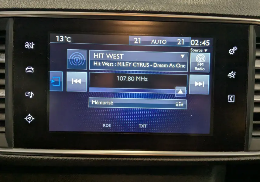 Écran central tactile de la Peugeot 308 noir affichant la radio FM sur la station Hit West à 2h45.