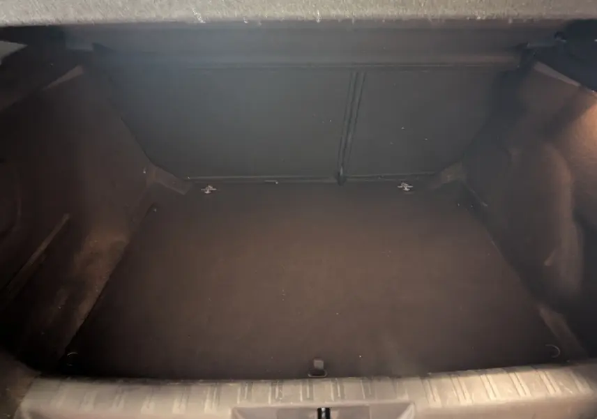 Coffre vide en vue plongeante d'une Peugeot 308 noire 1.2 PureTech 110 Style, intérieur sombre et propre.