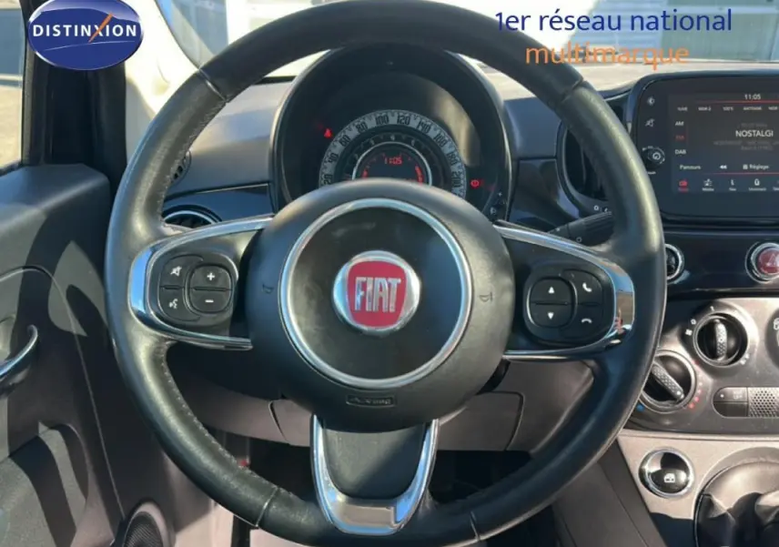 Vue rapprochée du volant noir de la Fiat 500 Lounge 2016 avec tableau de bord et écran tactile visible.