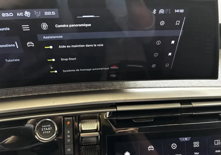 Vue rapprochée de la console centrale du Peugeot 5008 gris clair, avec écran tactile et bouton start/stop visible.