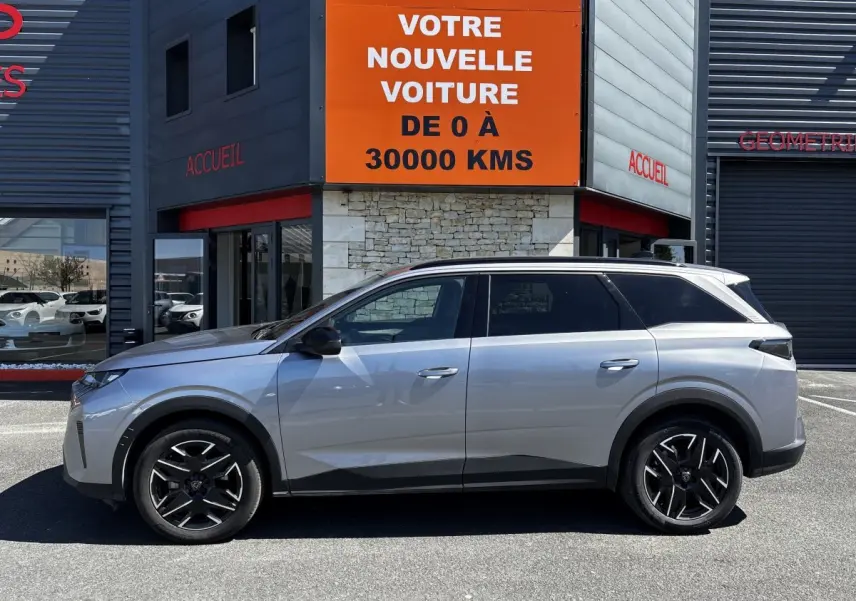 Profil côté gauche du Peugeot 5008 gris clair 2025, SUV hybride avec jantes noires et toit noir.