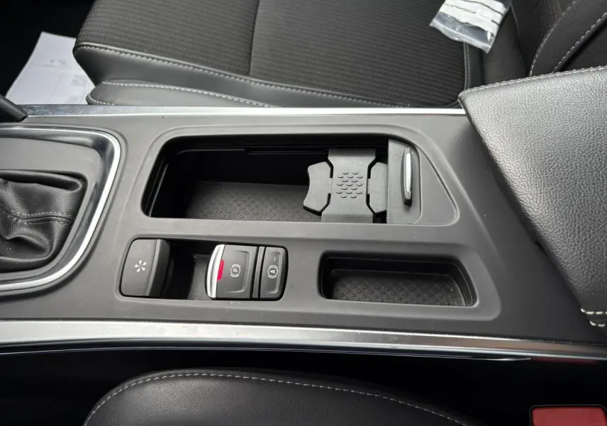 Vue rapprochée de la console centrale noire avec commandes de frein à main électrique et rangement sur Renault Mégane Break 2024.
