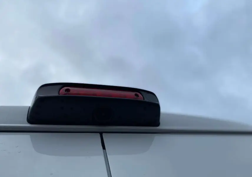 Gros plan sur la caméra de recul intégrée au feu stop supérieur arrière du Citroën Jumper blanc.
