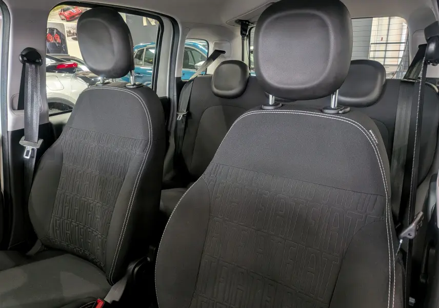Vue intérieure rapprochée des sièges avant en tissu noir avec logo FIAT embossé, dans une Fiat Panda 2025.