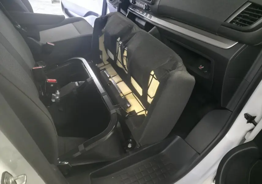 Vue intérieure côté droit du coffre sous la banquette relevée d'un Opel Vivaro blanc, montrant le rangement intégré.