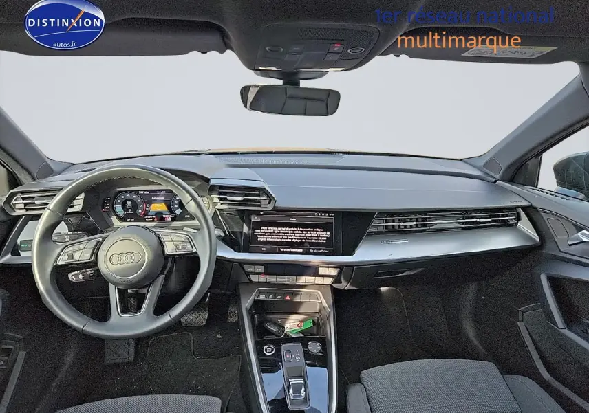 Vue frontale de l'habitacle de l'Audi A3 Sportback 2024 avec tableau de bord moderne et volant cuir 3 branches.