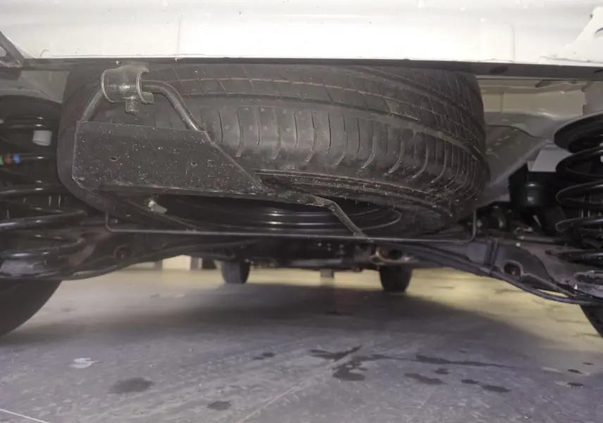 Vue en contre-plongée sous un Opel Vivaro blanc, montrant la roue de secours montée sous le châssis.