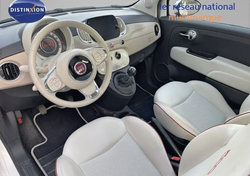 Intérieur avant droit de la FIAT 500 blanche 1.0 Hybrid 70ch DolceVita avec volant beige et sièges cuir clair.