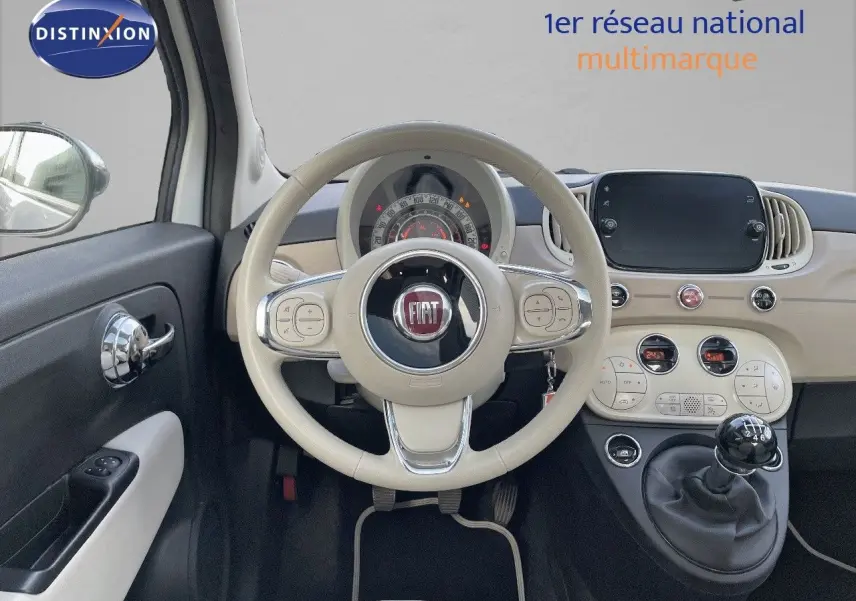 Vue intérieure centrée sur le volant beige et tableau de bord clair de la Fiat 500 blanche 1.0 Hybrid 2022.
