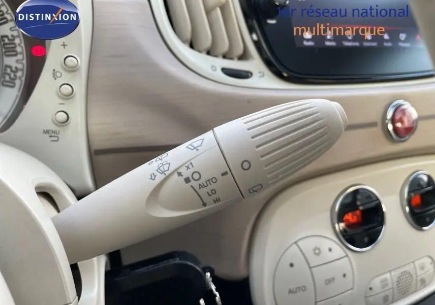 Gros plan sur la manette d'essuie-glace beige dans l'habitacle clair d'une Fiat 500 blanche, version DolceVita 2022.