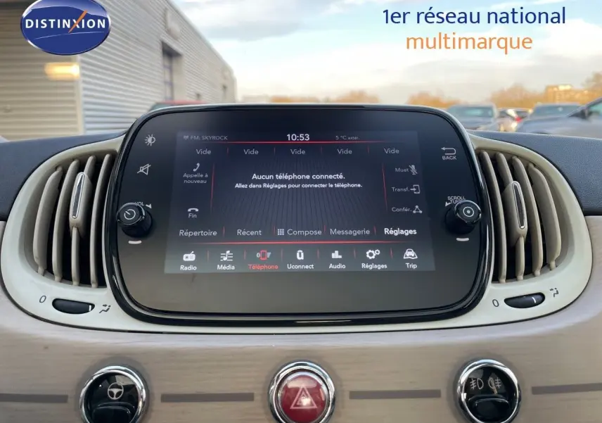 Écran tactile central avec interface multimédia allumée dans l’habitacle clair d’une Fiat 500 blanche.