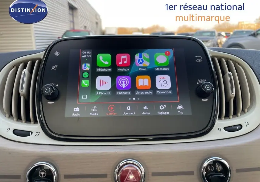 Écran tactile central affichant Apple CarPlay dans l'habitacle clair d'une Fiat 500 blanche, vue de face.